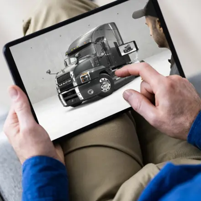 Person using a tablet to view a 3D model of a black Mack truck, interacting with the display.