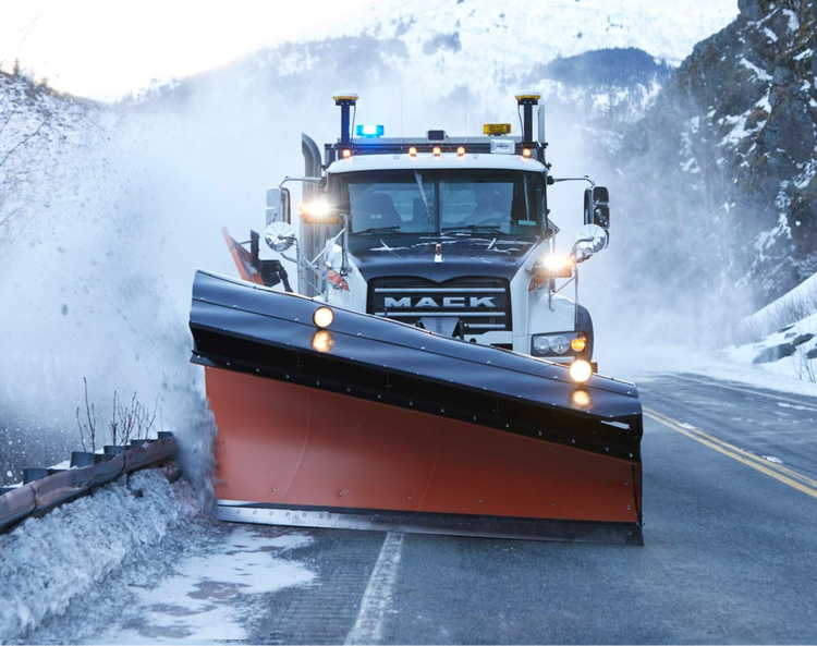 Mack truck with an orange snowplow clearing snow on a mountain road