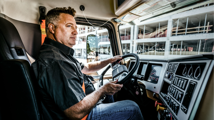 Driver operating a Mack truck equipped with a D-shaped steering wheel, showcasing a comfortable and ergonomic design