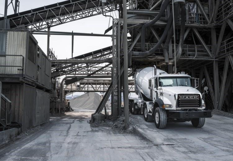 White Mack cement mixer truck driving through an industrial facility