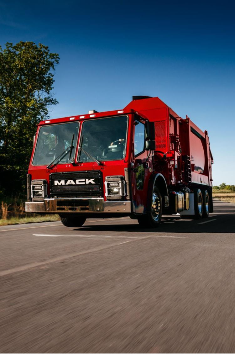 A red Mack LR Series truck, designed for refuse collection with a durable cab and bold Mack branding