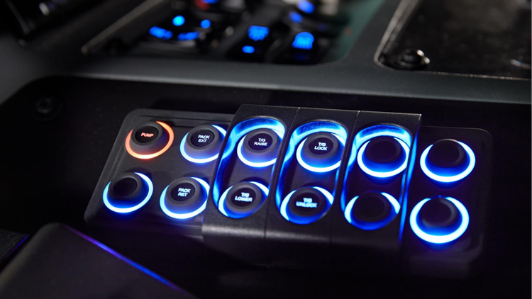 Close-up of the integrated control panel in a Mack truck, featuring backlit buttons with blue and orange illumination for streamlined vehicle operation