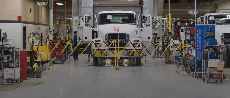 White Mack truck on the production line in a manufacturing facility.
