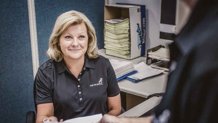 Mack Trucks staff member assisting a customer at a desk.