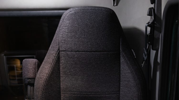 Mack MD Series driver's seat with a gray fabric finish and armrest.