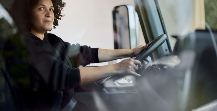 Driver confidently operating a Mack MD truck, focused on the road.