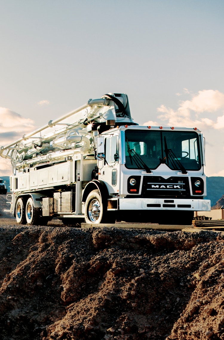 White Mack TerraPro truck with a concrete pump, parked on a construction site