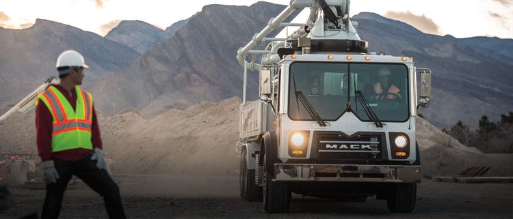 Mack TerraPro truck in action on a construction site, with an engineer overseeing the work.